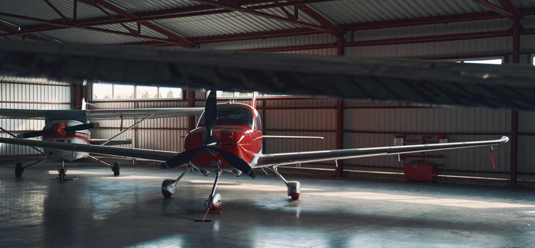 Two red and white planes in a dimly lit hangar