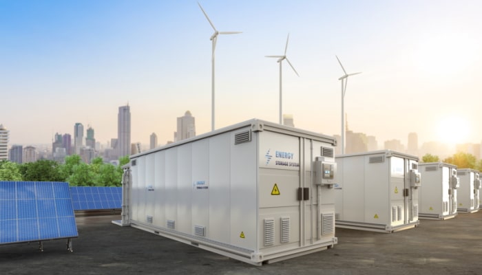 Electrical boxes and solar panels with a city skyline and wind turbines in background