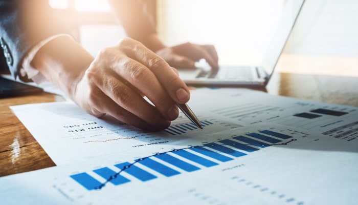 Hand pointing at graphs on desk with a pen