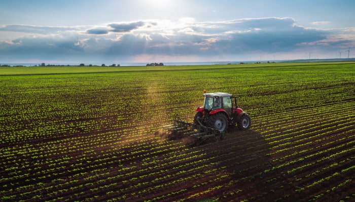 Red tractor plowing a field