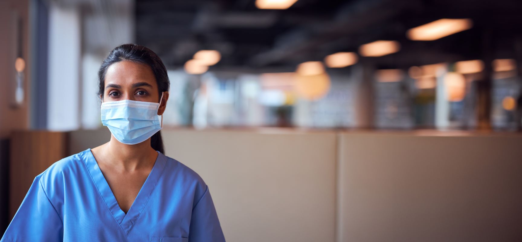 Medical professional in scrubs wearing a mask