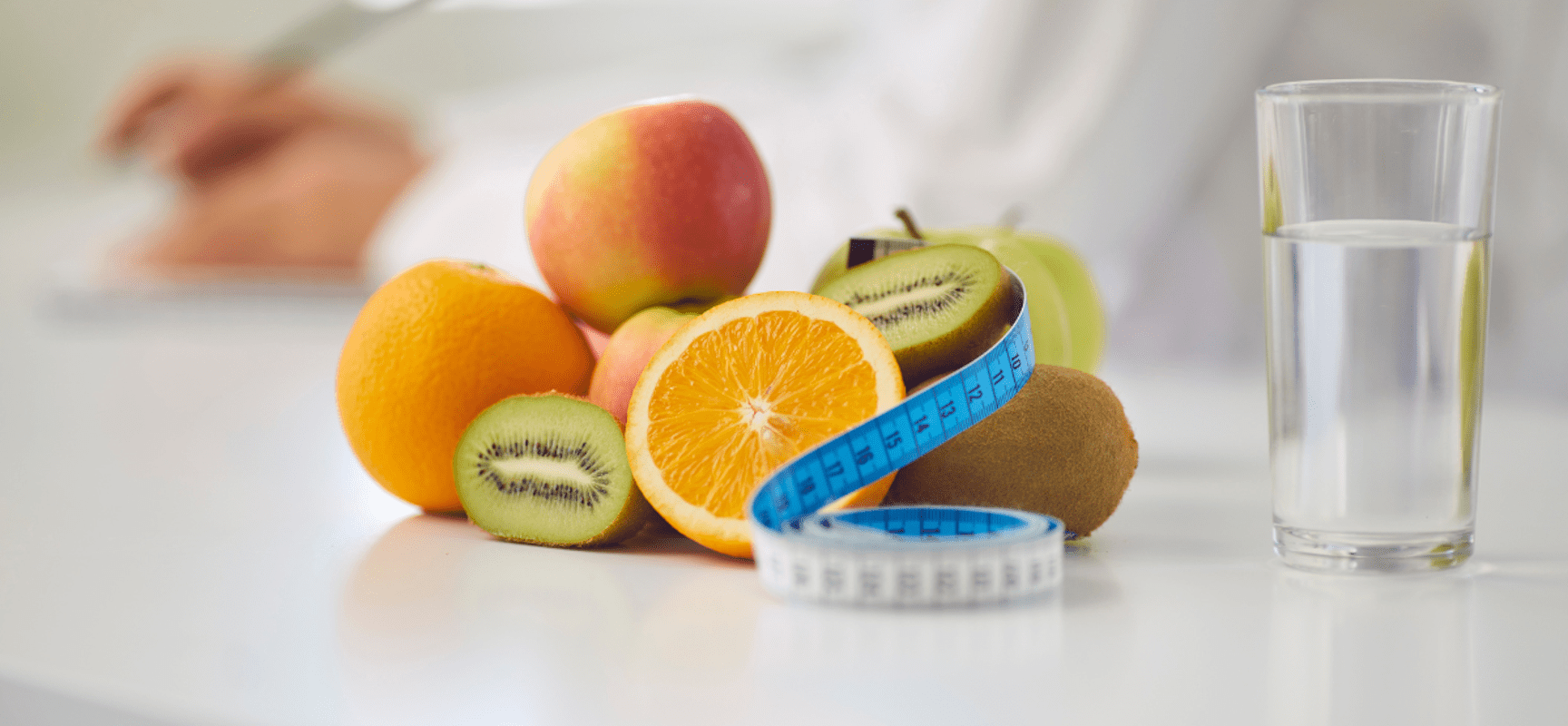 Colorful fruit on a table with a measuring tape and glass of water
