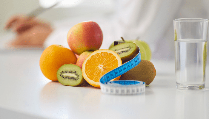 Colorful fruit on a table with a measuring tape and glass of water