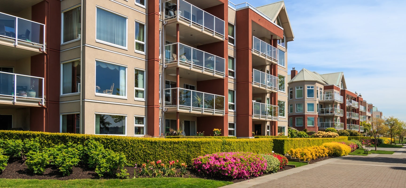 Apartment building on a sunny day with colorful trimmed hedges