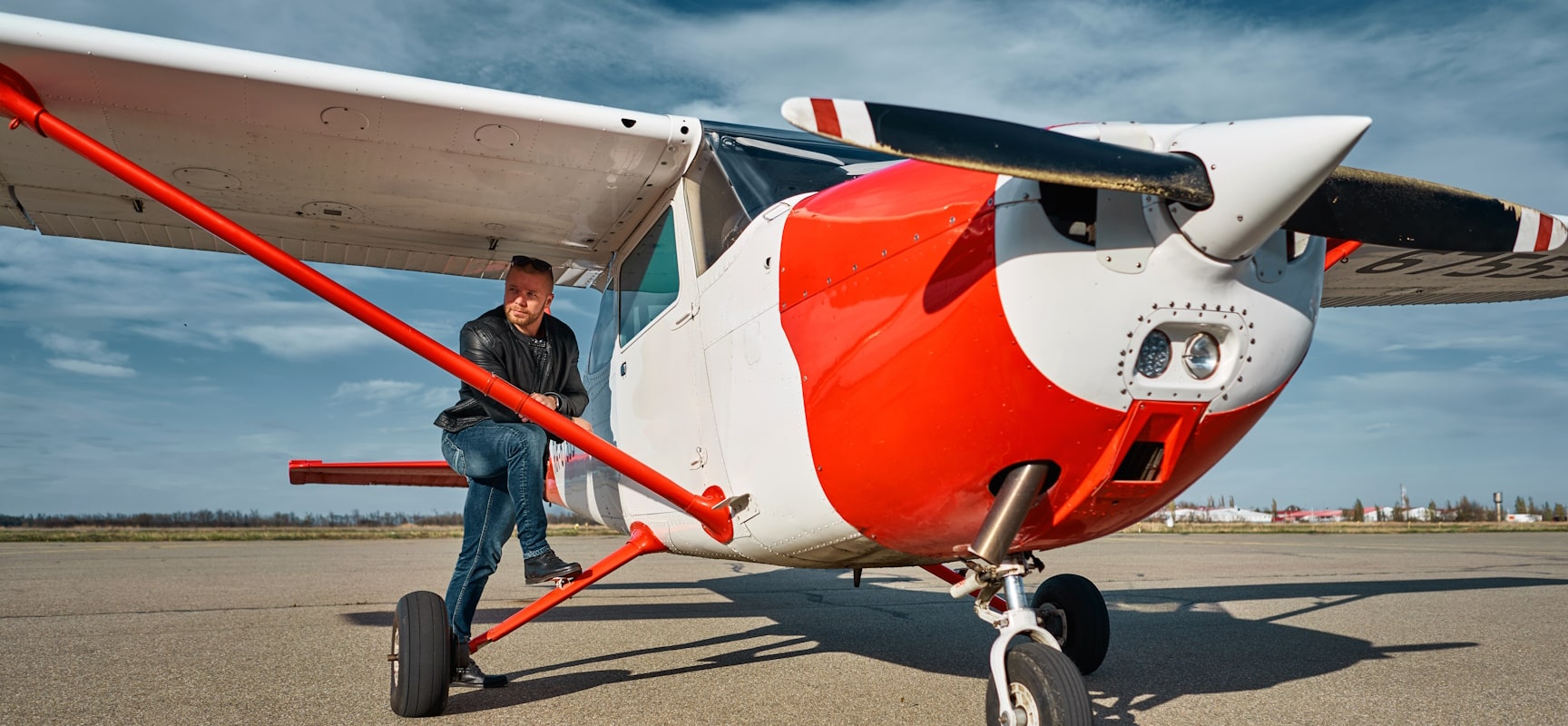 Man leaning against red and white airplane