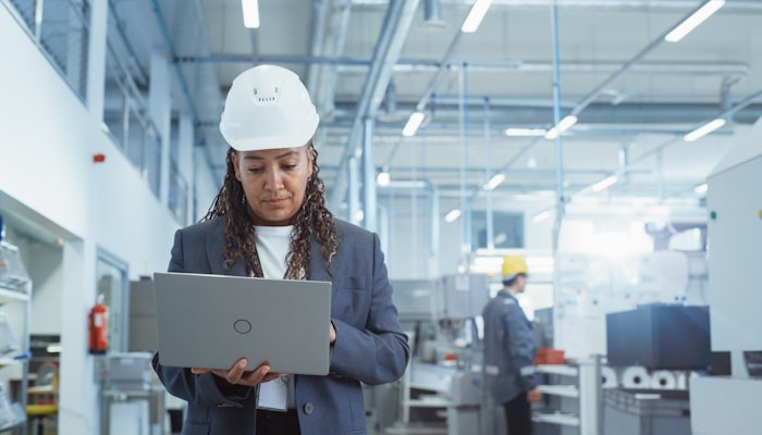 Woman in a hardhat holding a laptop